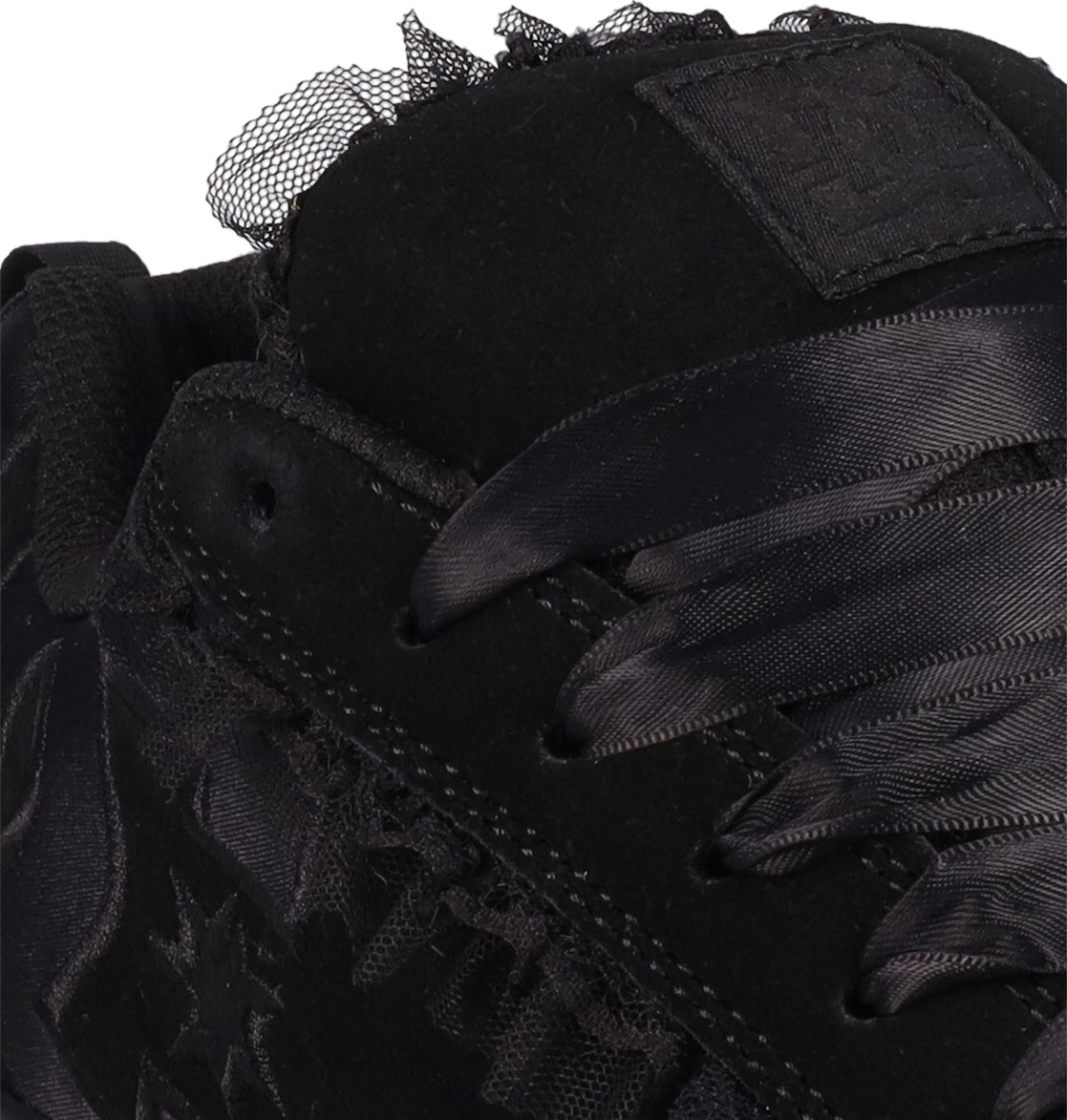 Close-up of DC Shoes Women's Court Graffik SD sneaker in black, showcasing a puffy silhouette, satin laces, black embroidery details, mesh accents, and a stitched logo patch on the tongue.