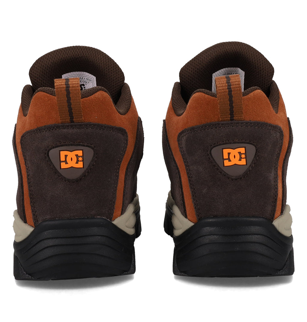 A pair of Men’s Recon OG Shoes by DC Shoes is displayed side by side on a white background, showcasing their brown and orange colorway with black and beige soles. The DC logo appears on the heel, emphasizing the shoes’ sturdy build and urban style.
