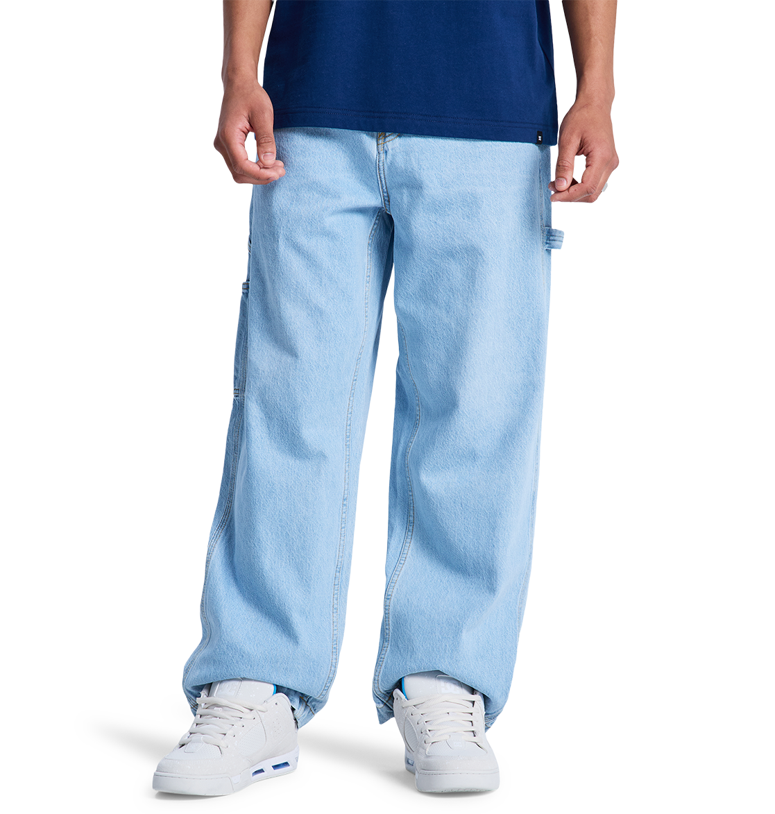A person wears DC Shoes Men's Baggy Denim Carpenter Pant in light blue, paired with a dark blue T-shirt and white sneakers. Only the lower half of the body is visible against a plain white background.